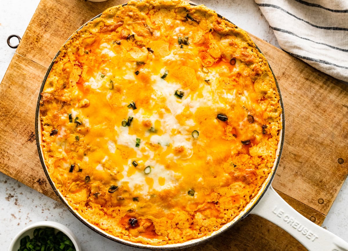 cheesy buffalo chicken dip in skillet on wood cutting board. 