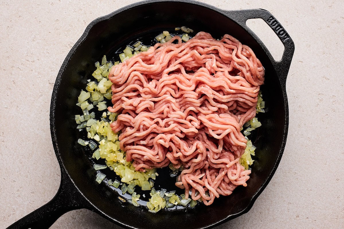 onion, garlic, and ground turkey cooking in cast iron skillet. 