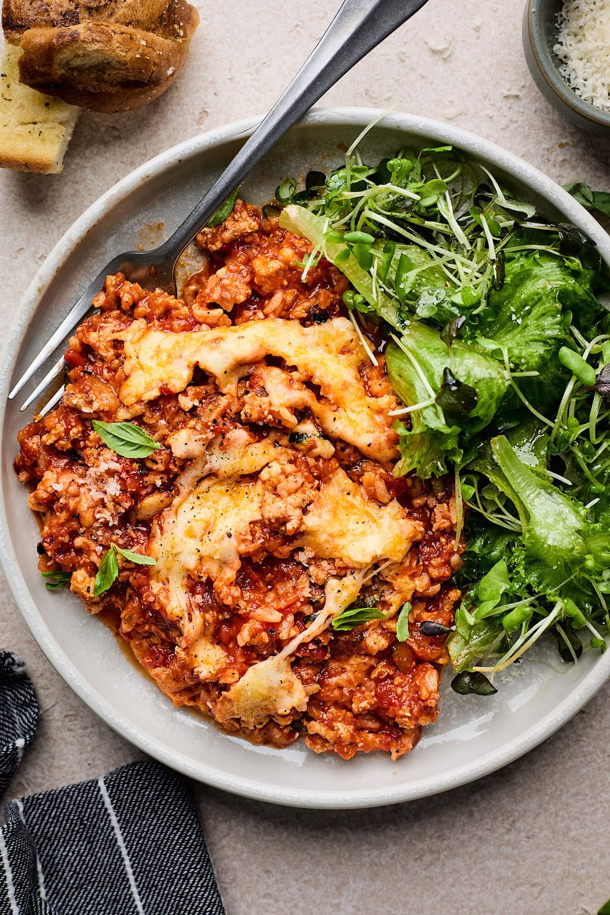 Cheesy Ground Turkey Rice Skillet with Marinara Sauce on plate with green salad and fork. 