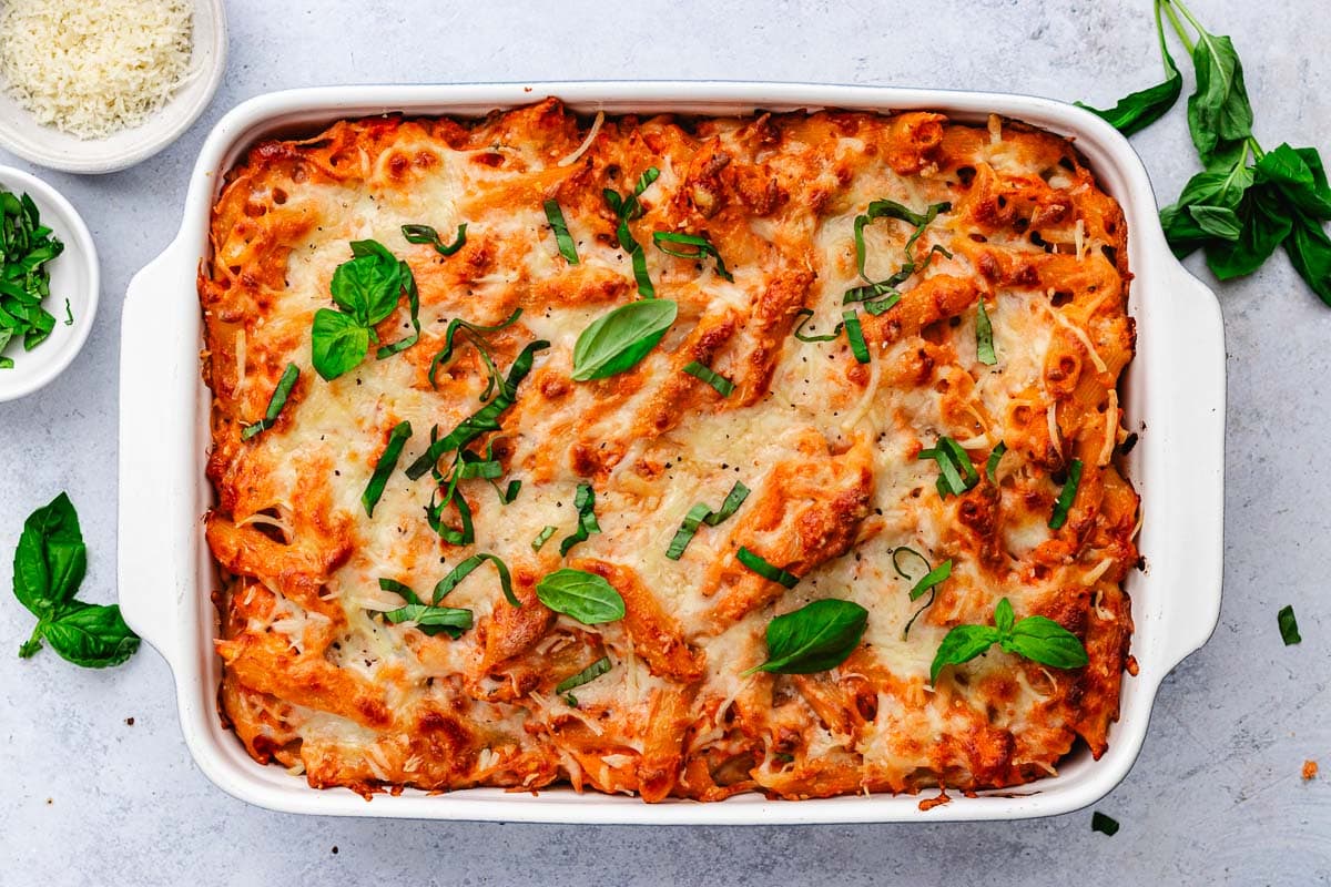 baked ziti in pan with fresh basil. 