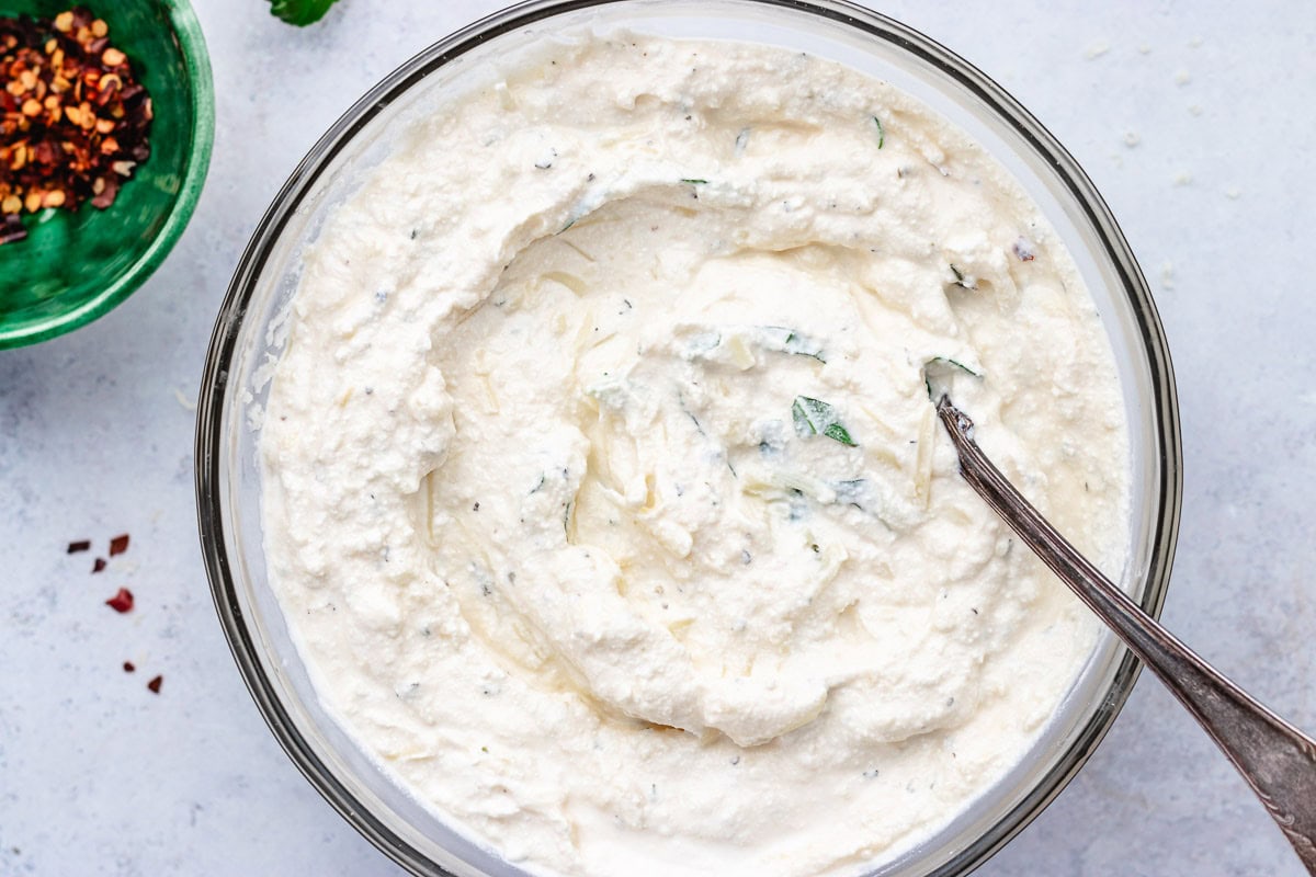 ricotta cheese mixture in mixing bowl with spoon to make baked ziti. 