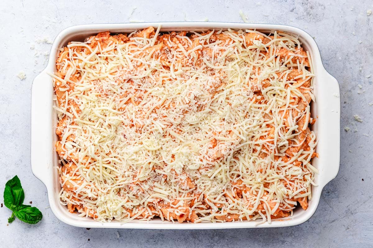 baked ziti topped with cheese in pan ready to go into the oven. 