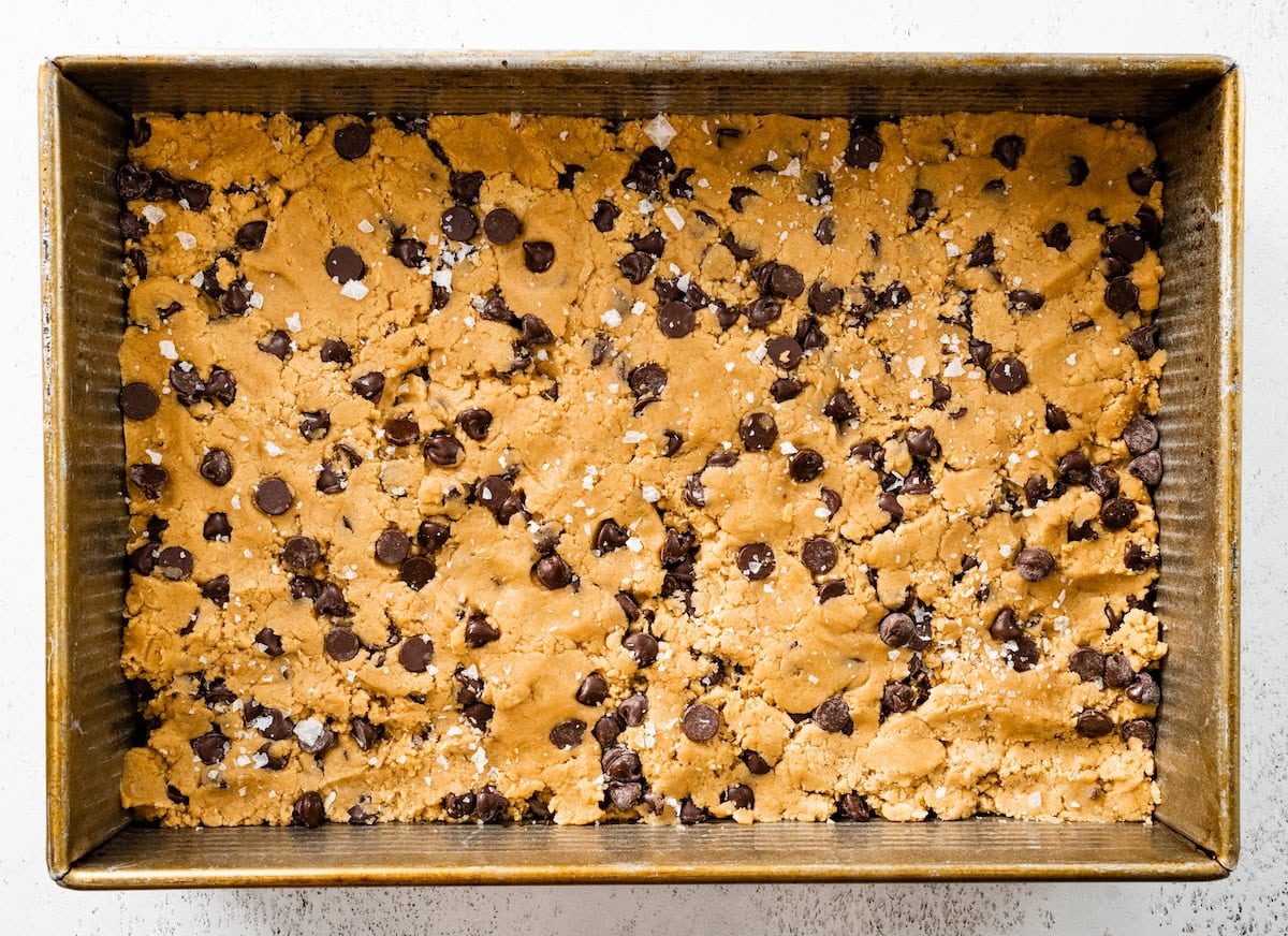 chocolate chip cookie dough pressed into baking pan ready to be baked. 