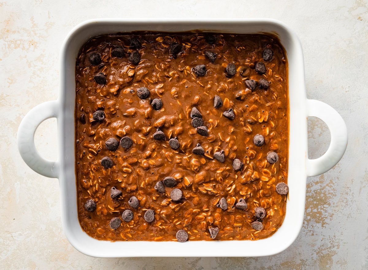 chocolate peanut butter baked oats batter in pan with chocolate chips sprinkled on top. 