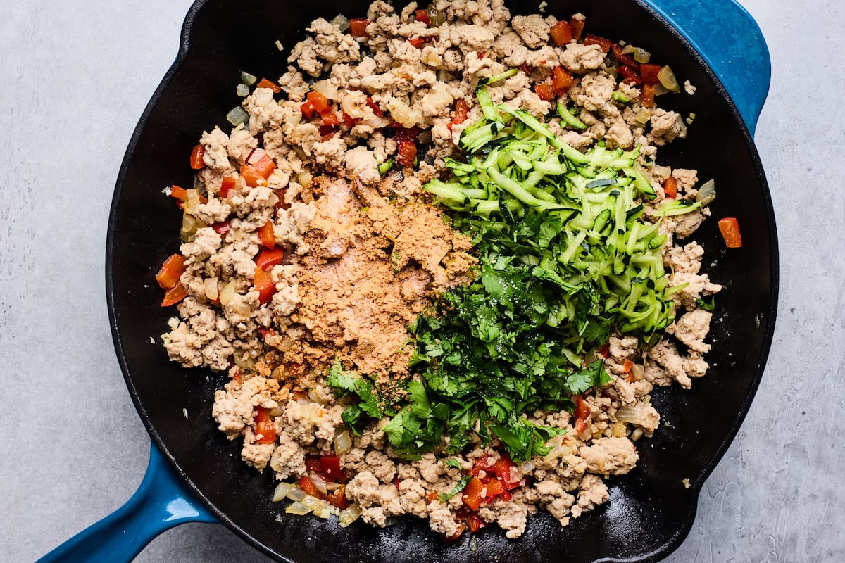 ground turkey with veggies, cilantro, and taco seasoning in skillet. 