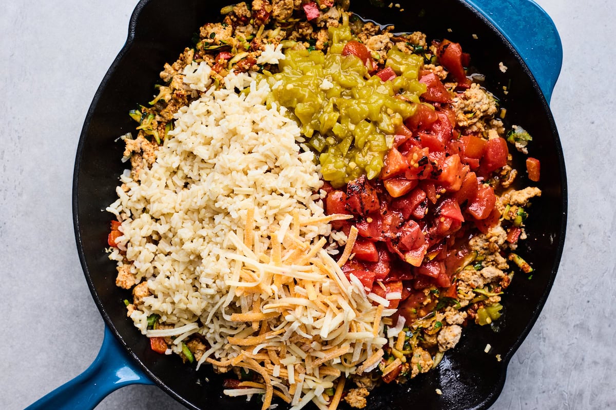 ground turkey in skillet with diced tomatoes, green chiles, rice, and cheese. 