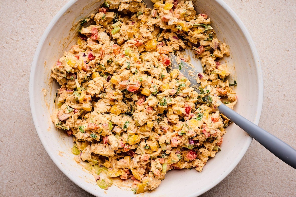 taco chicken salad being mixed together in bowl with spatula. 