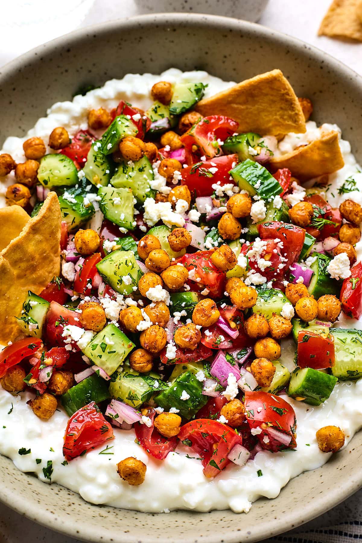 cottage cheese salad with crispy chickpeas, tomato, cucumber, red onion, feta, herbs, and pita chips. 