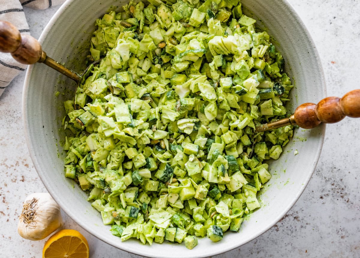 green goddess salad being tossed together in serving bowl. 