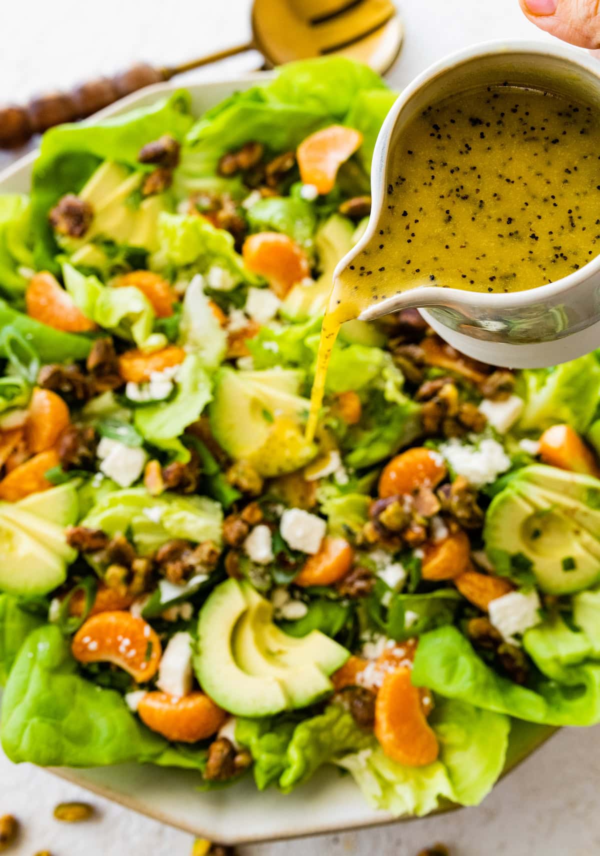 citrus poppy seed dressing being poured over mandarin orange salad. 