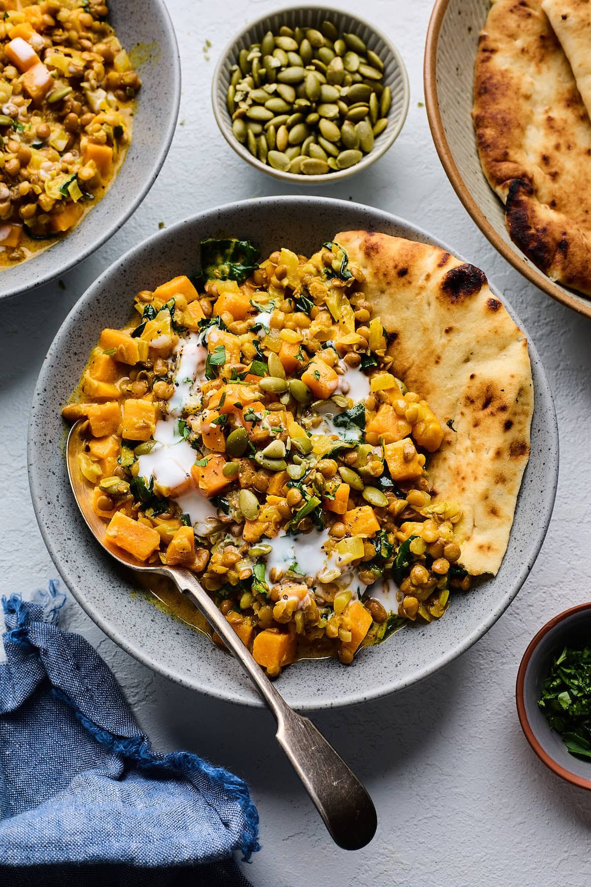 creamy sweet potatoes and lentils on plate with a drizzle of coconut milk and naan. 